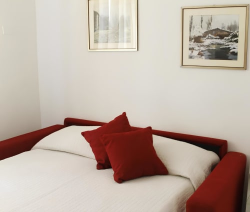 Modern bedroom at Ariel B&B Verona with red accents, white bedding, and framed landscape artwork