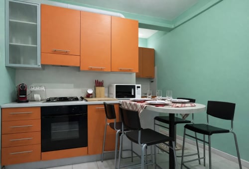 Modern orange kitchen in Ariel B&B Verona apartment with dining table and mint green walls