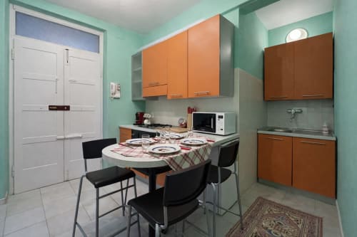 Modern kitchen-dining area at Ariel B&B Verona with turquoise walls, orange cabinets, and round dining table with black