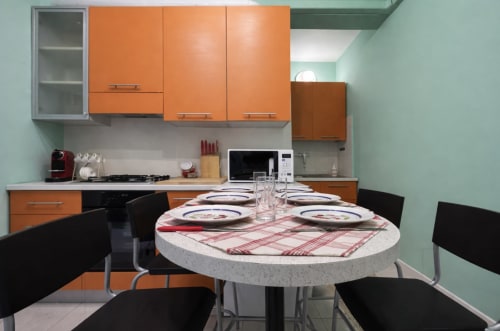 Modern kitchen and dining area at Ariel B&B Verona with orange cabinets, round table, and black chairs