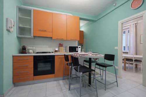 Modern kitchen with orange cabinets and dining area in Appartamento Nido at Ariel Bed & Breakfast Verona