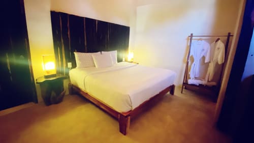 Moderna recámara en Ala Residencias Villa La Guardia, Chetumal, con ropa de cama blanca, cabecero oscuro e iluminación ambiental