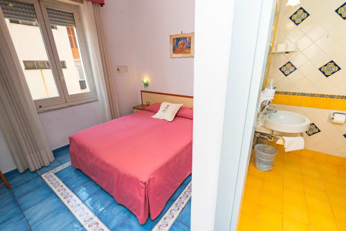 Letto rosa con vista sulla città nella camera economy di Casa Mannini B&B a Maiori, Italia, con bagno privato