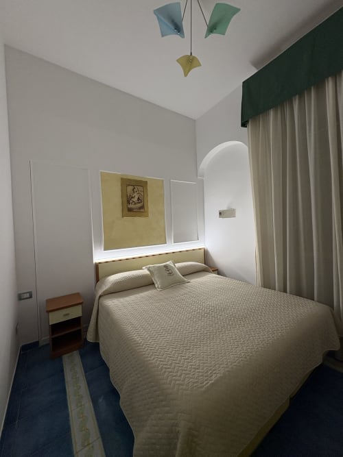 Camera accogliente in stile economy presso Casa Mannini B&B a Maiori con letto matrimoniale, testata specchiata e vista sulla città