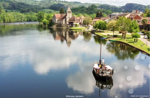 Vue pittoresque de l'église médiévale et du village des Instants Volés en Dordogne, France avec bateau traditionnel
