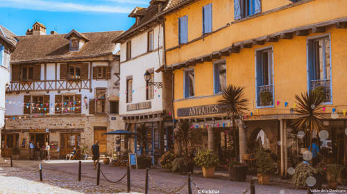 Place médiévale de Tudèls avec ses bâtiments colorés et boutiques, près des Instants Volés