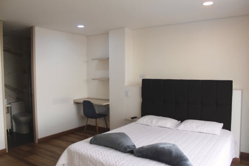 Apartaestudio Modelia Living en Bogotá con cama queen, cabecera negra, escritorio de trabajo y baño moderno