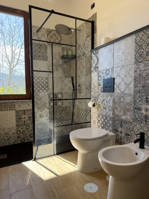 Bagno moderno con piastrelle decorate, doccia a cascata e bidet nella camera con vista montagna di B&B Luna Verde