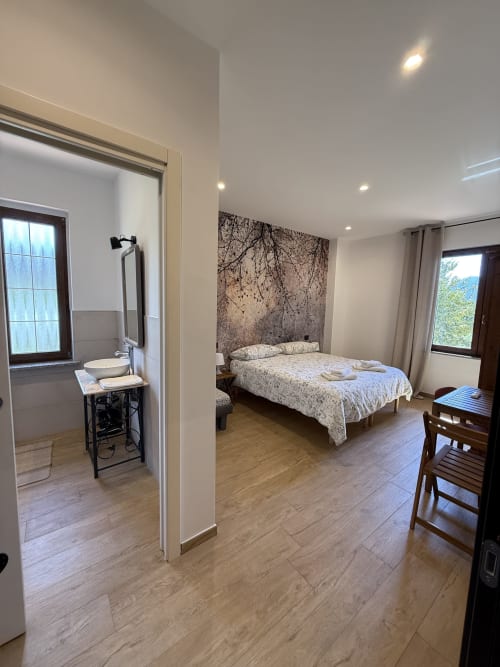 Camera moderna a Luna Verde B&B con letto matrimoniale, carta da parati con vista montagna, bagno en-suite, pavimenti in legno e zona pranzo