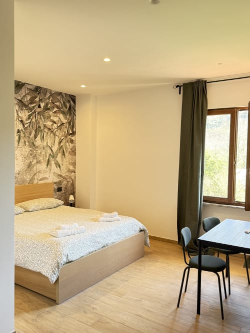 Camera moderna della B&B Luna Verde con letto in legno, scrivania, finestre con vista giardino e arredamento contemporaneo