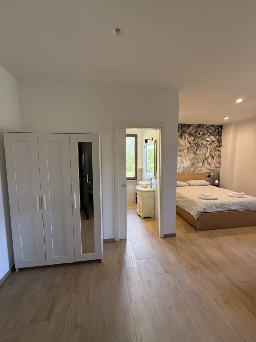 Camera moderna a B&B Luna Verde con armadio bianco, pavimenti in legno, letto con testiera decorata e bagno privato