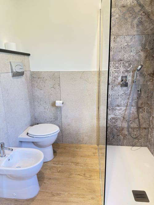 Bagno moderno in B&B Luna Verde con sanitari bianchi, bidet e ampia doccia con piastrelle decorate