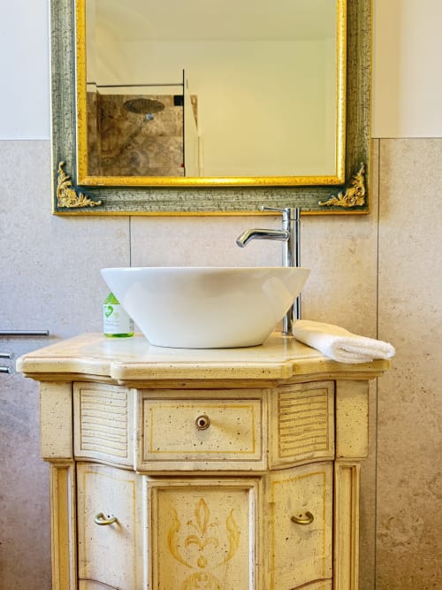 Elegante lavabo con lavandino in ceramica bianca, mobile in legno e specchio ornamentale presso B&B Luna Verde