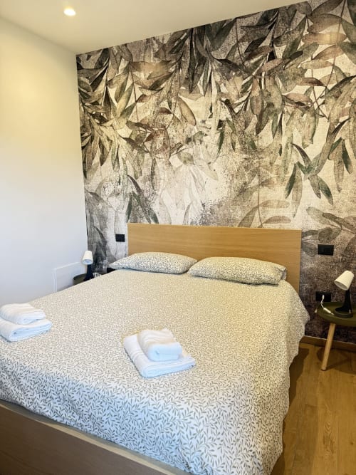 Camera da letto Luna Verde B&B con letto matrimoniale, testata in legno, carta da parati a motivi botanici e vista giardino