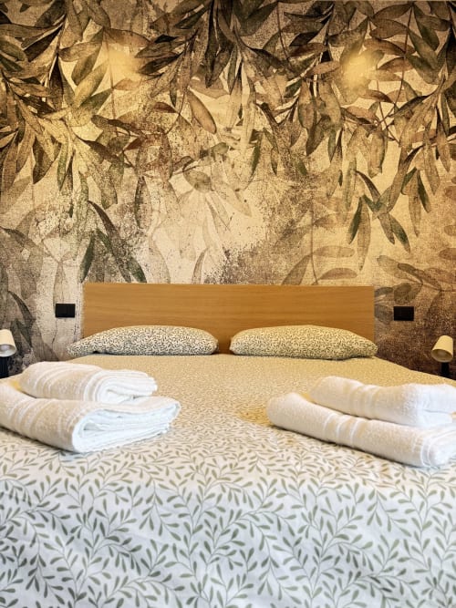 Letto matrimoniale ampio con asciugamani arrotolati bianchi, testiera in legno, biancheria floreale e carta da parati botanica nella Suite 104 del B&B