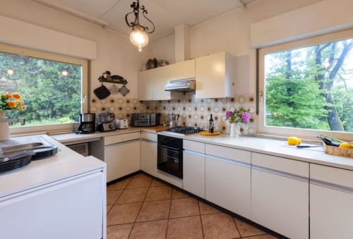Cucina moderna con cabinetry bianco, rivestimento geometrico, piano cottura a gas e ampie finestre con vista sul Lago d'Orta