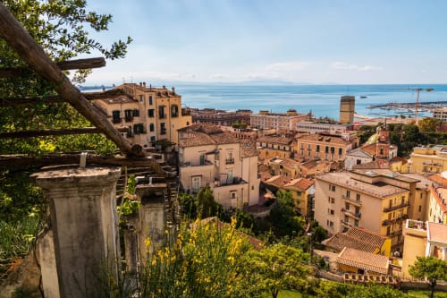 Vista di affascinante borgo costiero con edifici in terracotta, porto marino e paesaggio mediterraneo presso la B&B Luna Verde