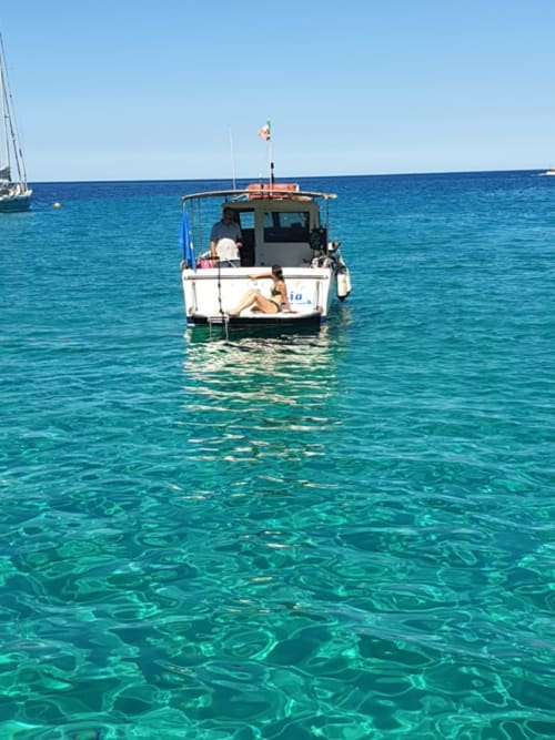 Barca da pesca ancorata nelle acque cristalline turchesi di Stintino, Italia presso Pescaturismo Lia
