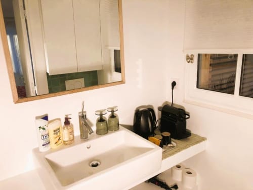 Salle de bain moderne à la Maison d'hôtes Versailles avec lavabo blanc, miroir et accessoires de toilette chez Denis & Virginie