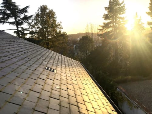Vue du lever de soleil sur le toit d'ardoise et le paysage forestier depuis le balcon du gîte Denis & Virginie à Versailles