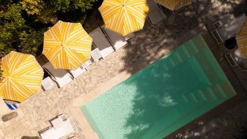 Vue aérienne de la piscine de l'Hôtel Le Sud avec parasols rayés jaunes et transats à Juan-les-Pins