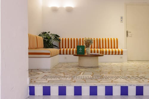 Espace de détente aux lignes épurées à l'Hôtel Le Sud à Juan-les-Pins avec coussins oranges et plantes décoratives