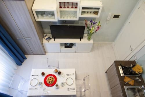 Junior Suite dining area with prepared meal at Exclusive Domus Gaudia Roma, TV and kitchenette visible