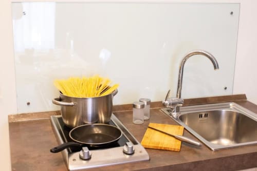 Junior Suite kitchenette at Domus Gaudia Roma with stovetop, cookware, sink, and backsplash