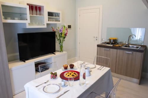 Junior Suite dining area at Exclusive Domus Gaudia Roma with kitchenette, TV, and table set for two