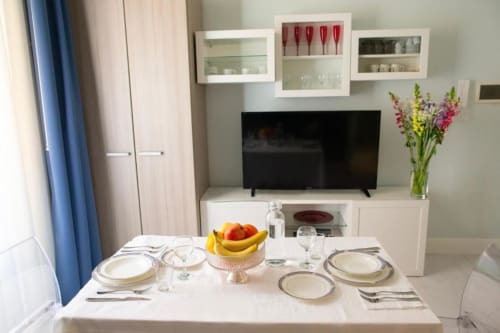 Elegant dining area in Junior Suite at Exclusive Domus Gaudia Roma, set table with place settings, fresh flowers, and TV