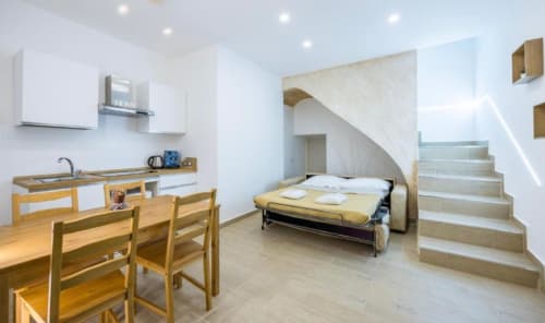 Moderno monolocale a Napoli con angolo cottura, zona pranzo, letto e scale per il livello superiore
