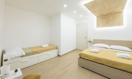 Camera moderna a Casa Fernanda, Napoli con due letti, pavimento in legno, angolo cottura e vista sulla città