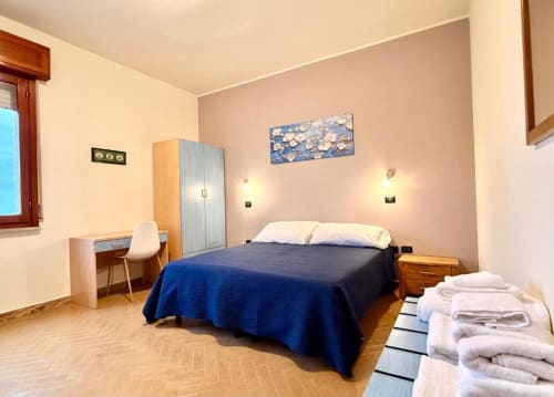 Bright apartment bedroom at Hotel Il Mulino in Villalunga with blue bed, desk, wardrobe and wood flooring