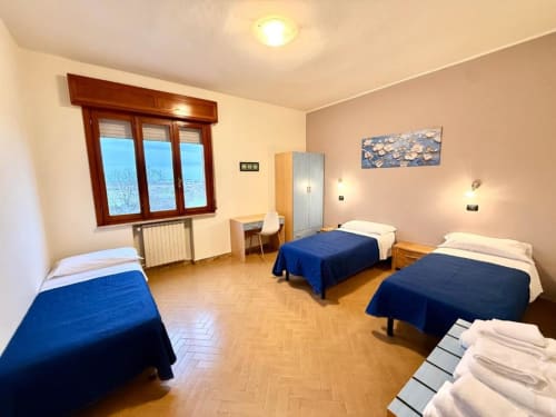 Bright multi-bed apartment room at Hotel Il Mulino in Villalunga with wooden floors and blue blankets