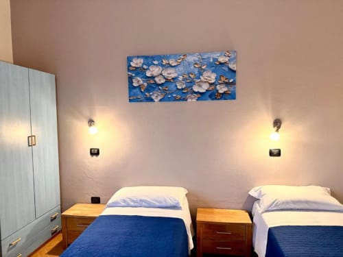 Twin bedroom in Appartamento Chiara at Hotel Il Mulino, Villalunga, with blue floral artwork and individual reading lights