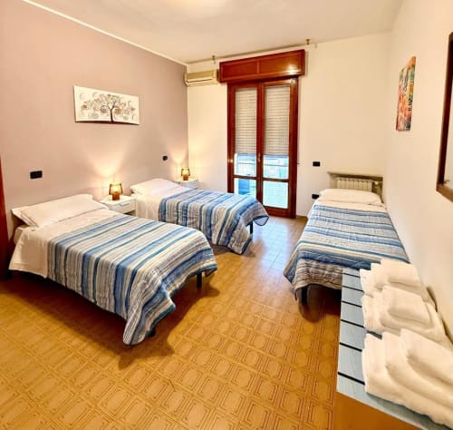 Triple bedroom at Hotel Il Mulino in Villalunga with blue striped beds and balcony access