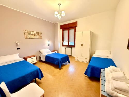 Bright triple bedroom at Hotel Il Mulino in Villalunga with blue bedspreads and wooden floors