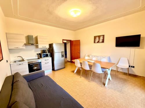 Bright open-plan apartment at Hotel Il Mulino featuring kitchen, dining table, sofa, and wall-mounted TV