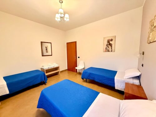 Bright multi-bed room at Hotel Il Mulino in Villalunga with blue blankets and wooden flooring
