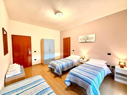 Bright bedroom at Hotel Il Mulino in Villalunga with three beds, wooden floors, and pink walls