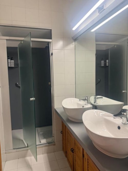 Bagno moderno presso Bronze Horse Affittacamere Firenze con tre lavabi bianchi in ceramica, box doccia in vetro e design contemporaneo