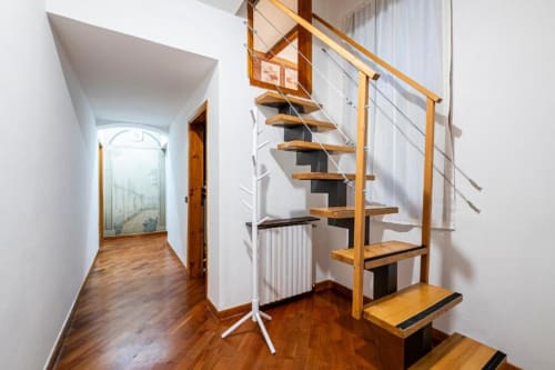 Moderna scala in legno nel corridoio di una B&B di Firenze con pareti bianche e pavimentazione in legno