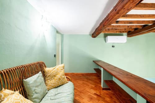 Camera accogliente all'Affittacamere Bronze Horse a Firenze con pareti verde menta, travi in legno e sedia in vimini