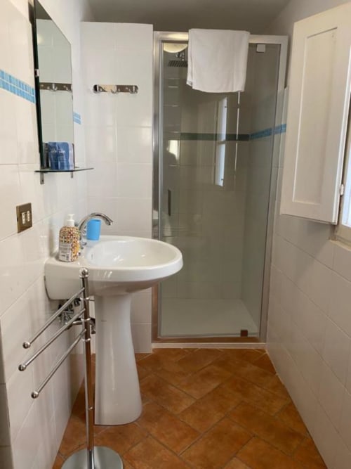 Modern bathroom at Bronze Horse Affittacamere with pedestal sink, glass shower enclosure, and blue tile accents in Florence