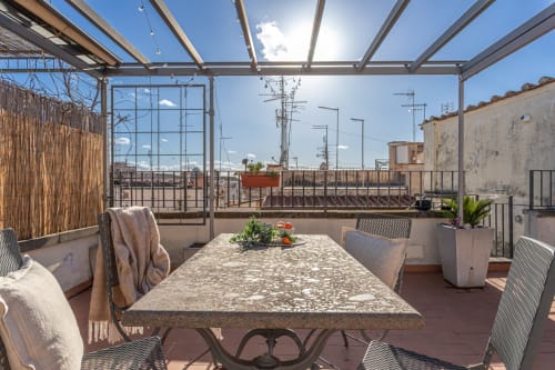 Terrazza panoramica di Terrestre Roma con tavolo da pranzo, pergolato moderno, vedute sulla città e piante rigogliose al sole