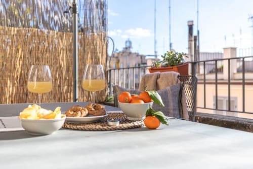 Colazione in terrazza a Terrestre Roma con succo d'arancia, pasticcini e frutta fresca con vista sul panorama di Roma