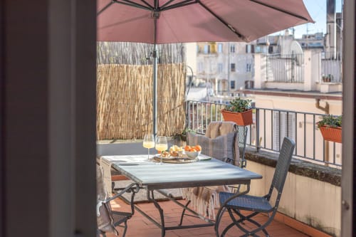 Terrazza con tavolo per cena, ombrellone, bicchieri di vino e vista sulla Colosseo a Roma