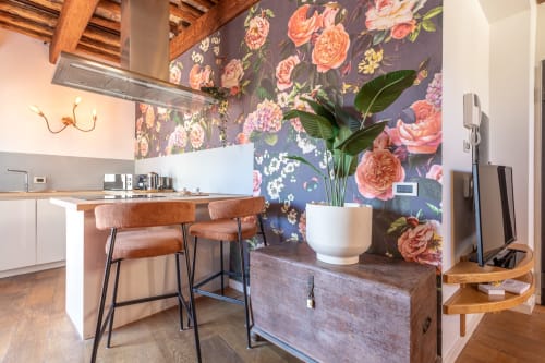 Cucina moderna con carta da parati floreale, travi in legno e banco bar nella penthouse della terrazza Terrestre Roma