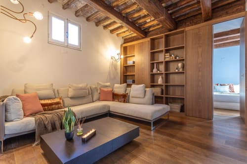 Penthouse con vista su Roma, travi di legno a vista, divano componibile color crema, librerie integrate e panorama sulla città