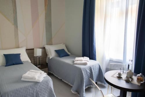 Twin bedroom at Exclusive Domus Gaudia Roma with city views, elegant striped headboard, and modern furnishings